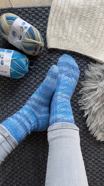 Blau gestreifte Socken mit Strukturmuster auf dunkelgrauen Teppich
